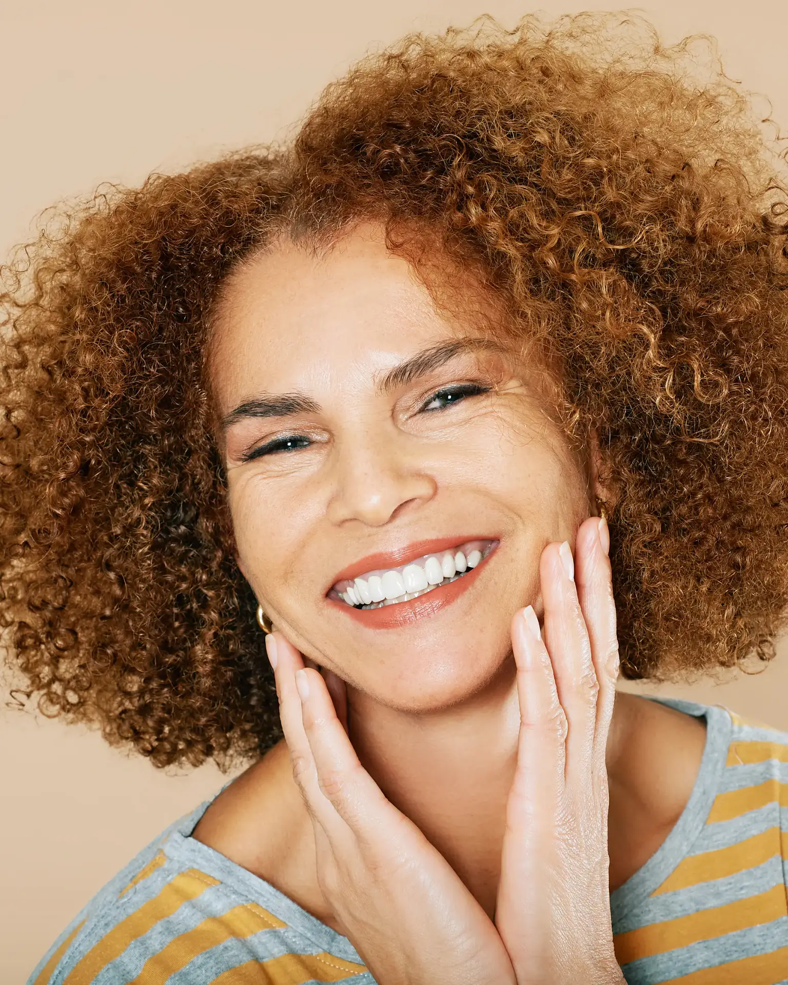 Smiling mature woman framing her refreshed facial contours with her hands, a good candidate for AlloClae in Augusta, GA
