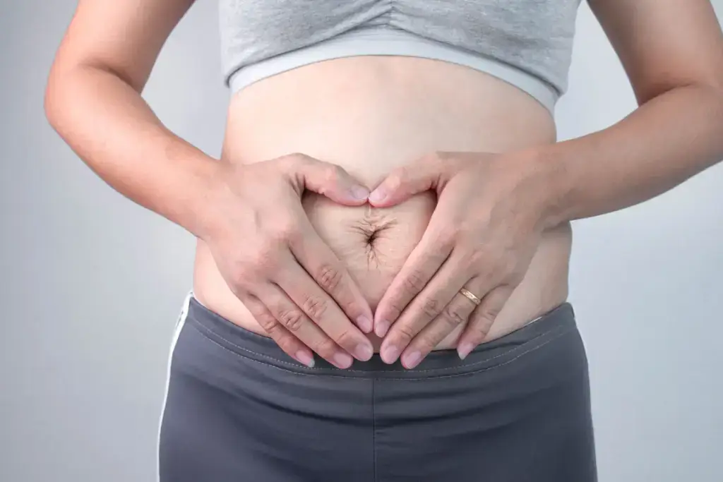 Woman holding her post-pregnancy belly, a common mommy makeover concern, in Augusta, GA